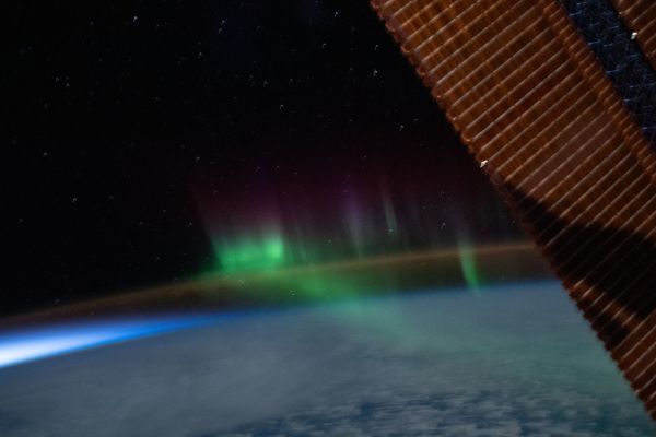A wispy 'aurora australis' intersects with the Earth's airglow